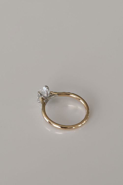Zoe engagement ring in 14k yellow gold with 14k ultra white gold setting, rear view showing the oval-cut diamond secured by a delicate criss-cross head design.
