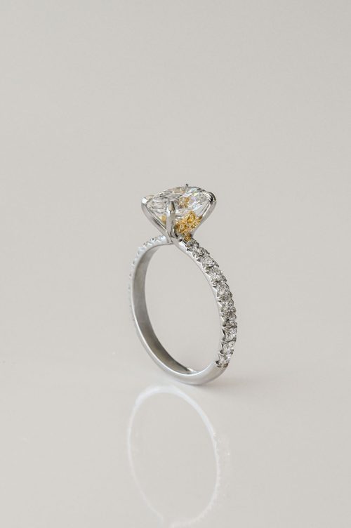 Florence engagement ring in 19k white gold with 18k yellow gold accents, featuring an oval diamond and pavé diamond band with hidden yellow detail beneath the center stone.