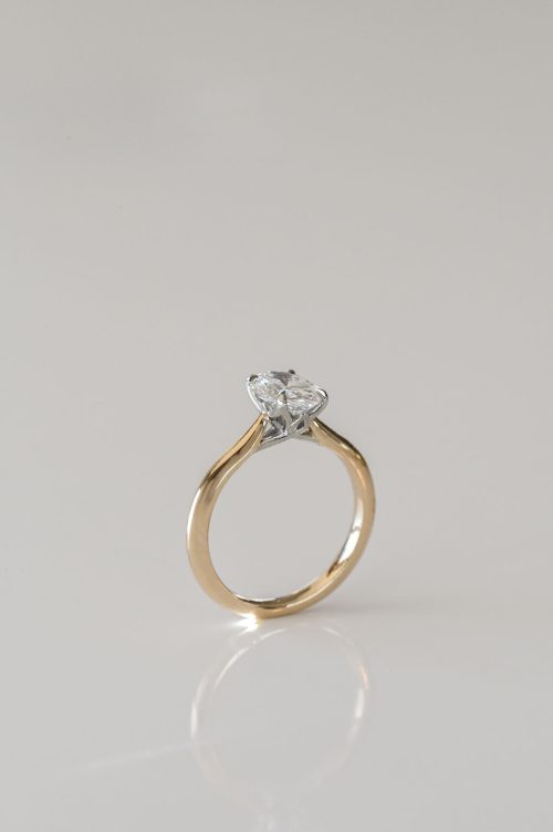 Olivia engagement ring in 14k yellow gold with 19k white gold setting, side view showing the oval diamond and criss-cross leaf-inspired details.
