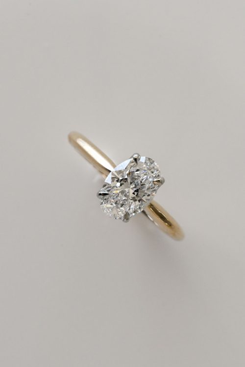 Olivia engagement ring in 14k yellow gold with 19k white gold setting, featuring an oval diamond cradled in a criss-cross, leaf-inspired design.