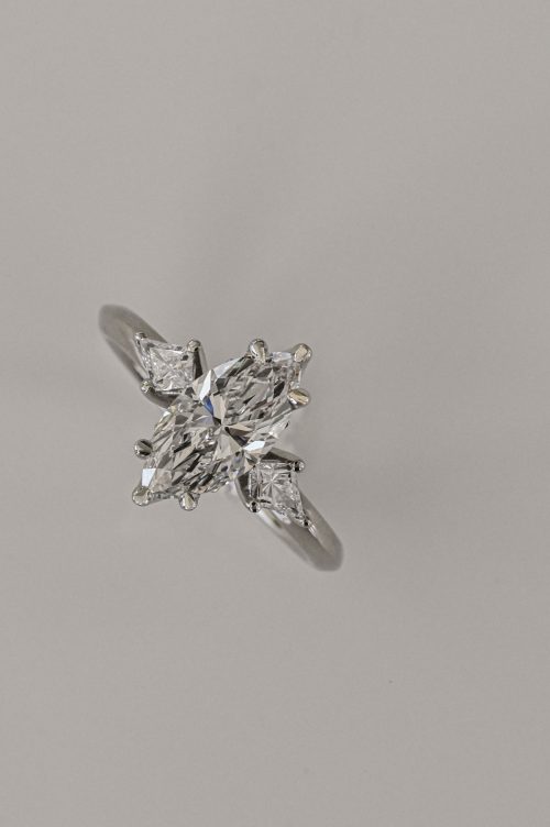 Violet three-stone ring in 14k ultra white gold, featuring a marquise center diamond with kite-shaped side stones in a petal-style setting.