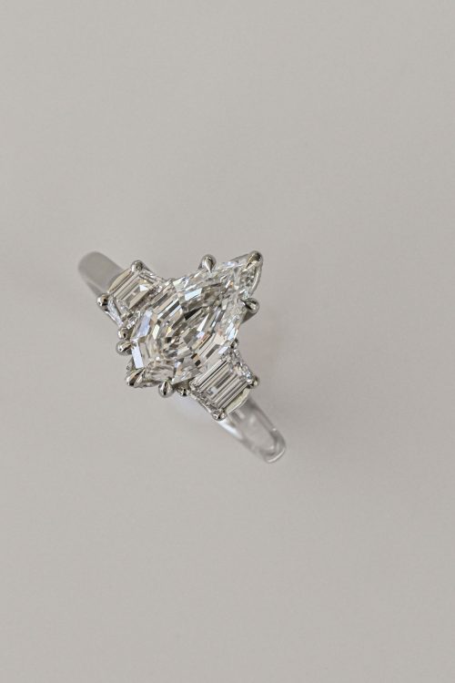 Sage three-stone ring in 14k ultra white gold, featuring a step-cut pear diamond with trapezoid shoulder stones.