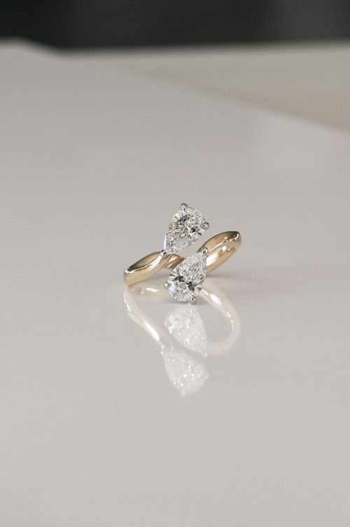 Open bypass ring in 14k yellow and ultra white gold, featuring two pear-cut lab-grown diamonds reaching toward each other.