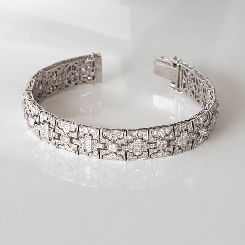 Art Deco bracelet in white gold with geometric panels, set with round and baguette diamonds in an intricate filigree design.