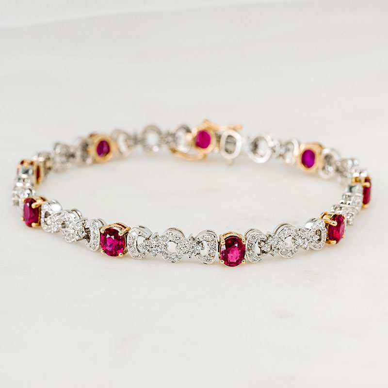 White and yellow gold bracelet featuring alternating oval rubies and round diamond clusters.
