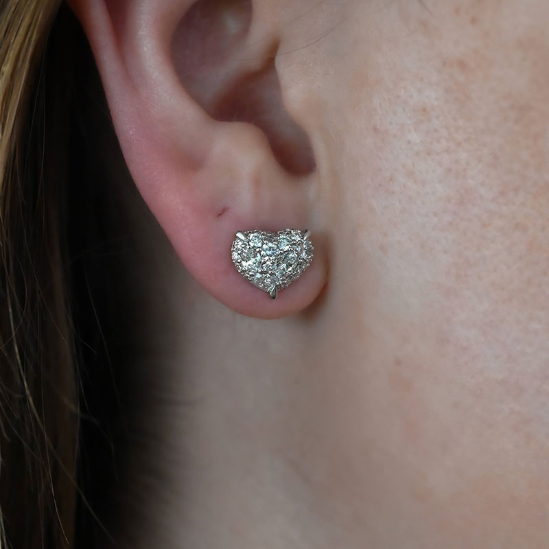 Heart-shaped diamond cluster stud earring in white gold, worn on the earlobe.