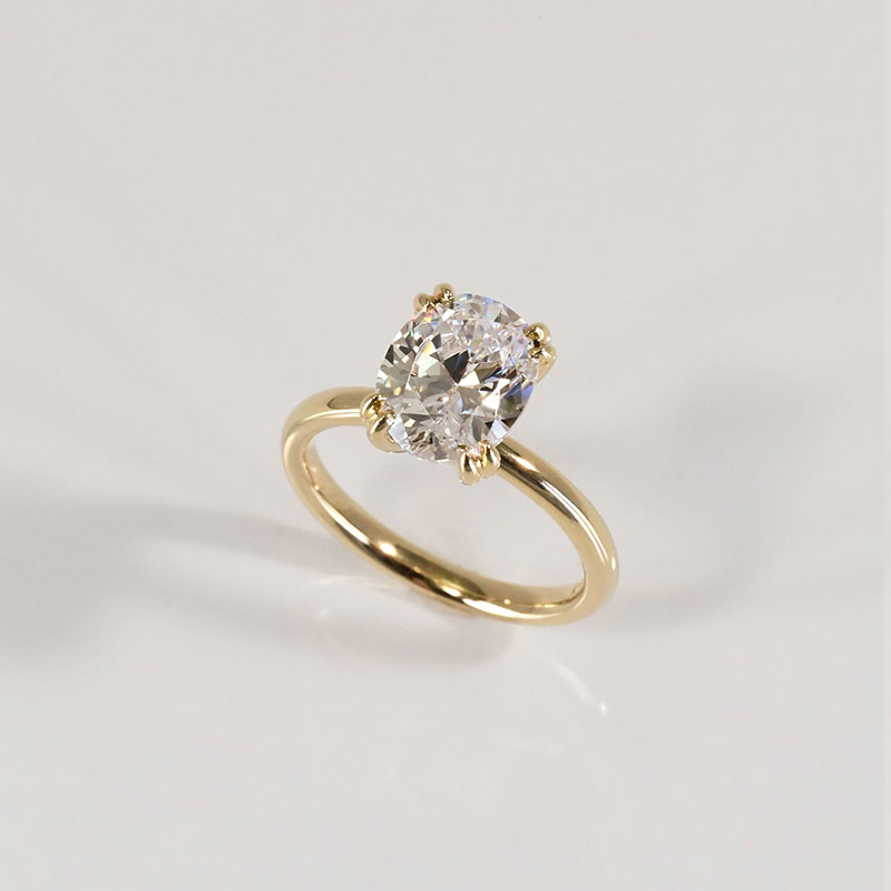 Oval-cut diamond engagement ring with a yellow gold band and four-prong setting.