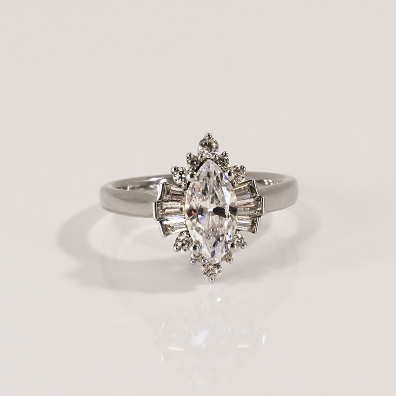 Marquise-cut diamond engagement ring in white gold, framed by a mixed halo of baguette and round accent diamonds.