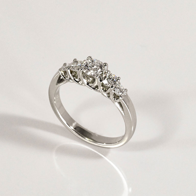 Five-stone diamond ring in white gold, featuring a graduated row of round brilliant diamonds in claw settings.
