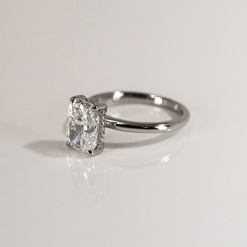 Platinum engagement ring with a cushion-cut diamond set in a pavé diamond halo.