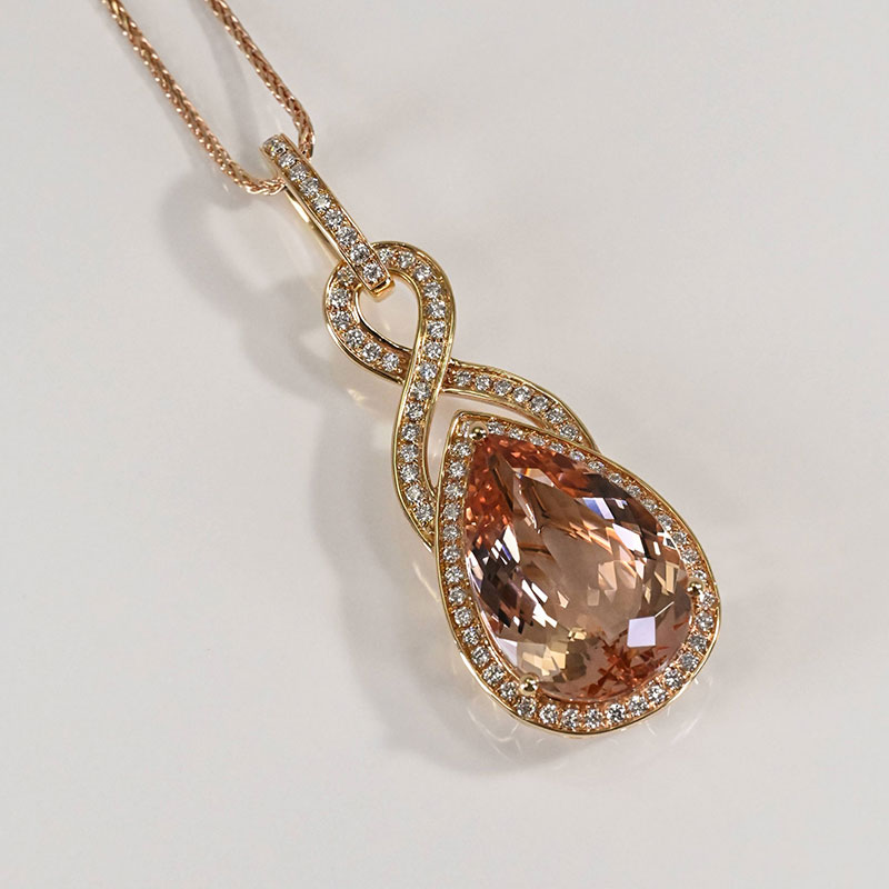 Rose gold necklace featuring a teardrop-shaped morganite pendant framed in a diamond halo and set in an infinity-inspired diamond loop design.