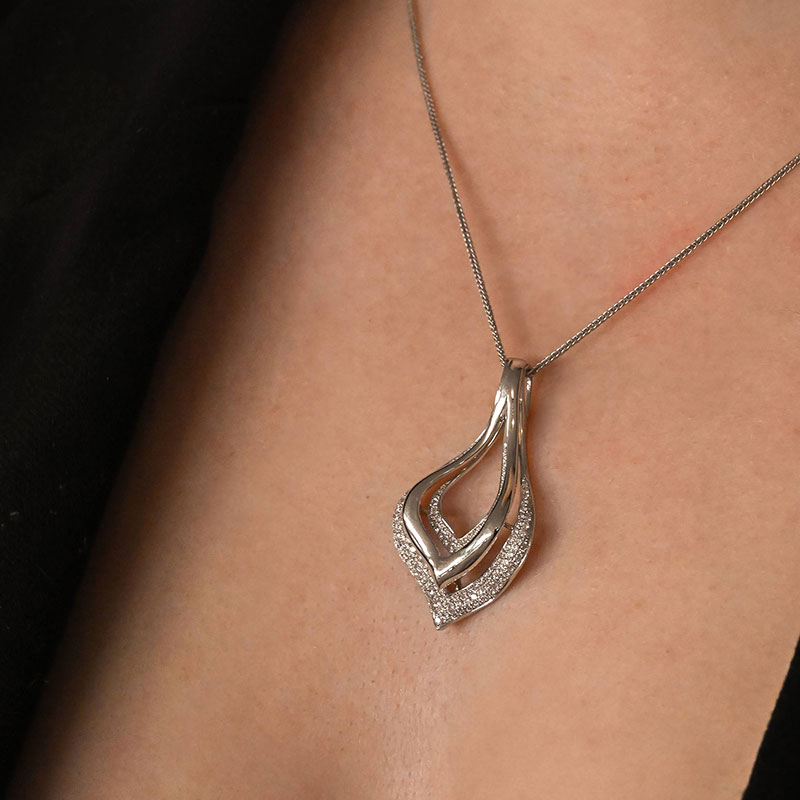 White gold pendant necklace featuring an abstract layered flame-shaped design with pavé diamond accents along the outer edge.