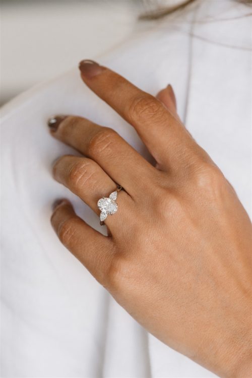 The Rae ring worn on the hand, featuring an oval centre diamond flanked by two marquise side stones set in a high-polish platinum band.