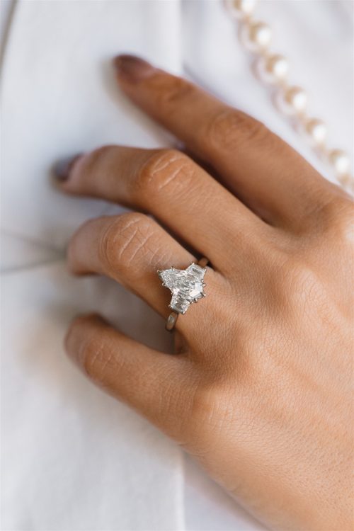 Close-up of the Sage ring featuring a white marquise diamond flanked by tapered baguette diamonds on a high-polish band.