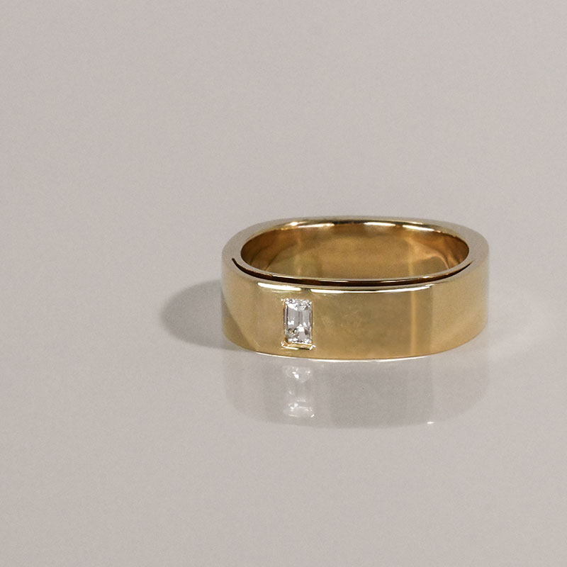High-polish yellow gold wedding band featuring a vertically set baguette-cut diamond.