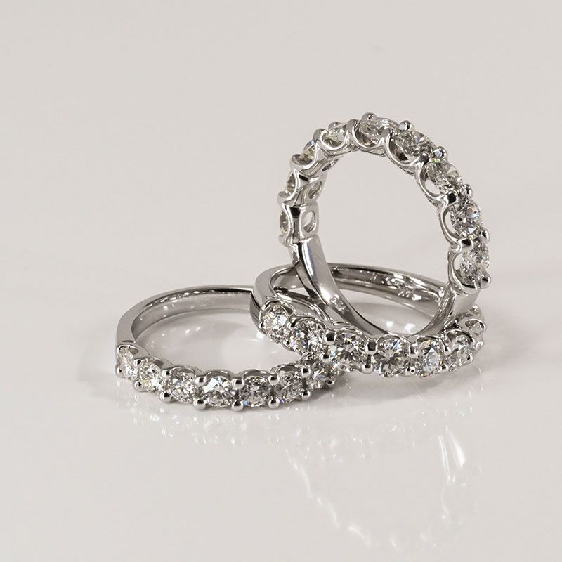 Trio of white gold bands featuring round brilliant diamonds in shared prong and scalloped settings.