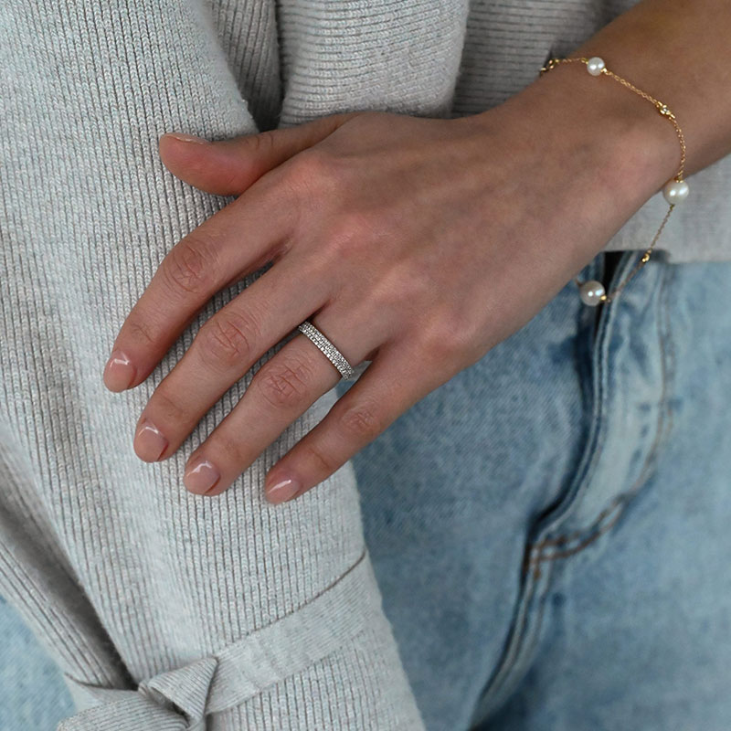 AnniversaryRings-2 Woman wearing a pavé diamond eternity band on her ring finger, styled with a gold bracelet and casual outfit.