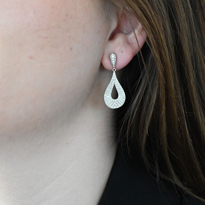 Woman wearing teardrop-shaped diamond pavé earrings with an open center design.