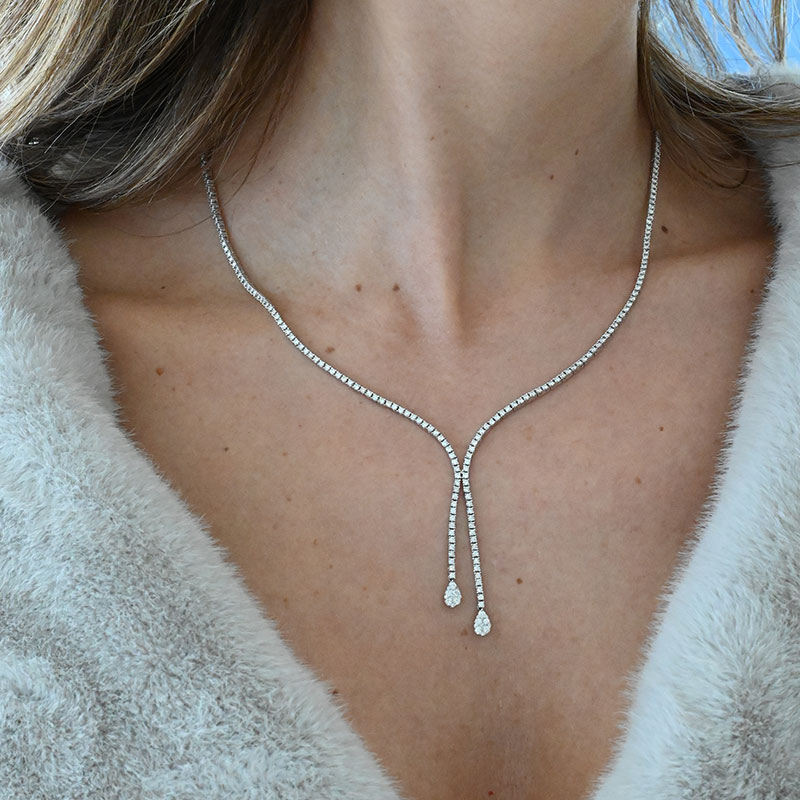 Woman wearing a Y-shaped diamond lariat necklace with two pear-shaped diamond drops.